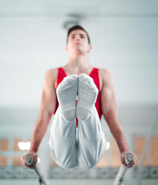 Man performing a controlled strength exercise in a dark gym.